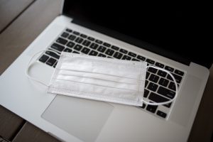 Open laptop with a paper mask sitting on the keyboard