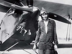 Amelia Earhart standing in front of her airplane